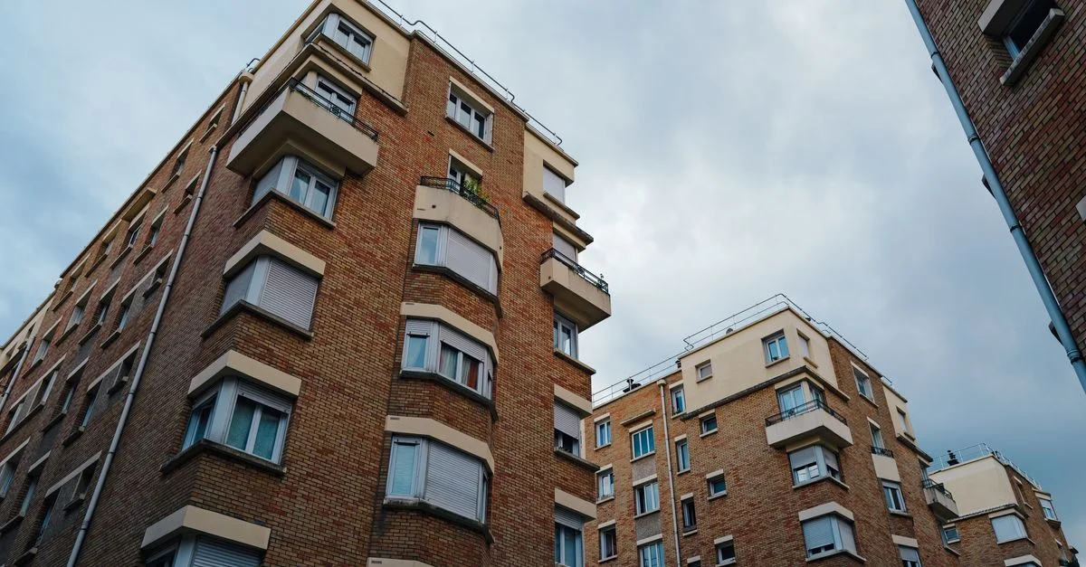 Bâtiments d'appartements en brique urbaine sous un ciel nuageux, mettant en valeur l'architecture de la vie citadine.