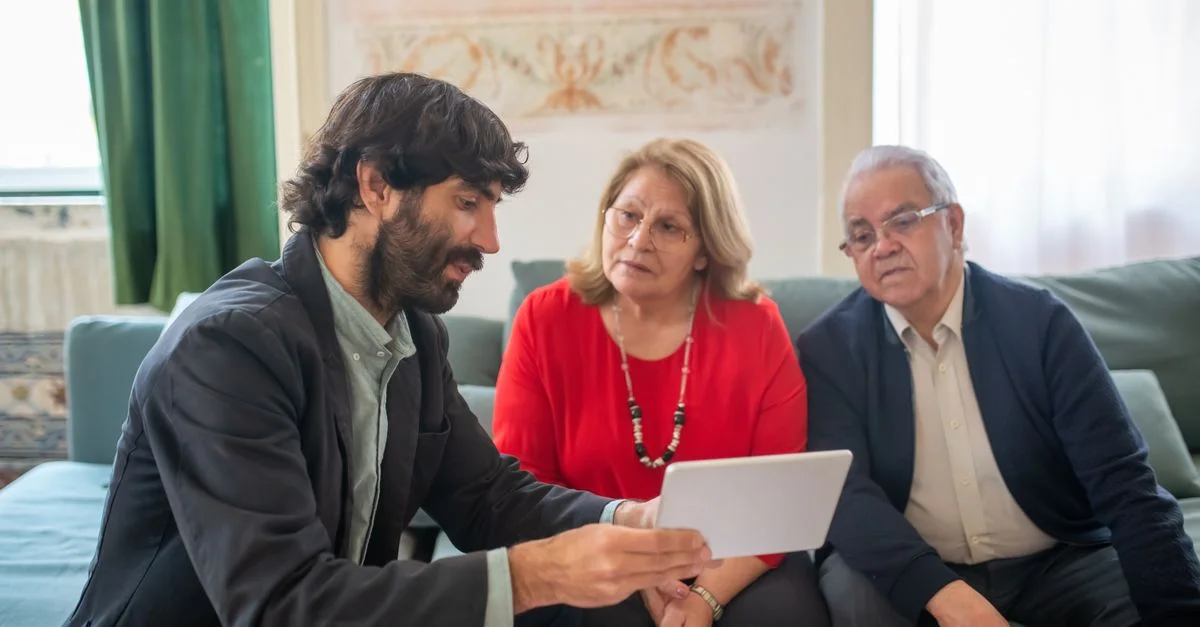 Un conseiller financier discutant des options d'investissement avec un couple de seniors dans un salon confortable.