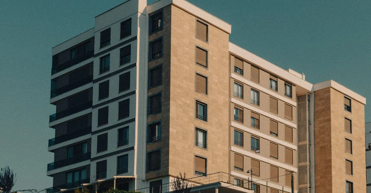 Un immeuble moderne avec une façade beige sous un ciel clair.