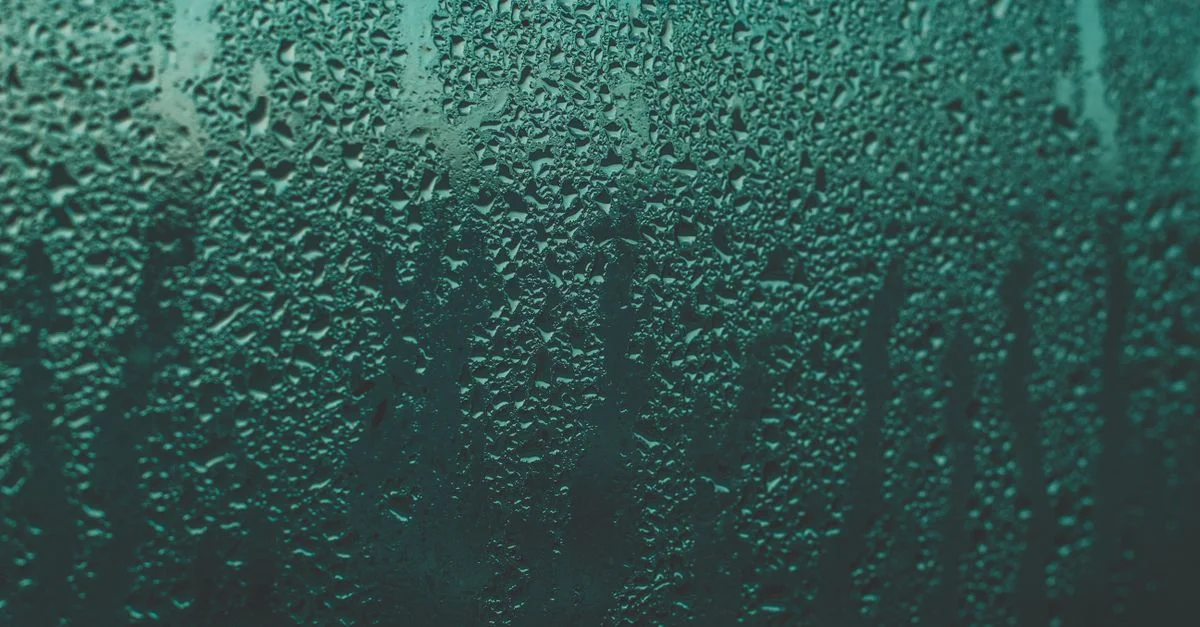Gros plan de gouttes de pluie sur une fenêtre créant une texture abstraite.