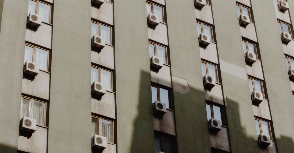 Façade d'un immeuble d'appartements en ville équipé de climatiseurs à chaque fenêtre.