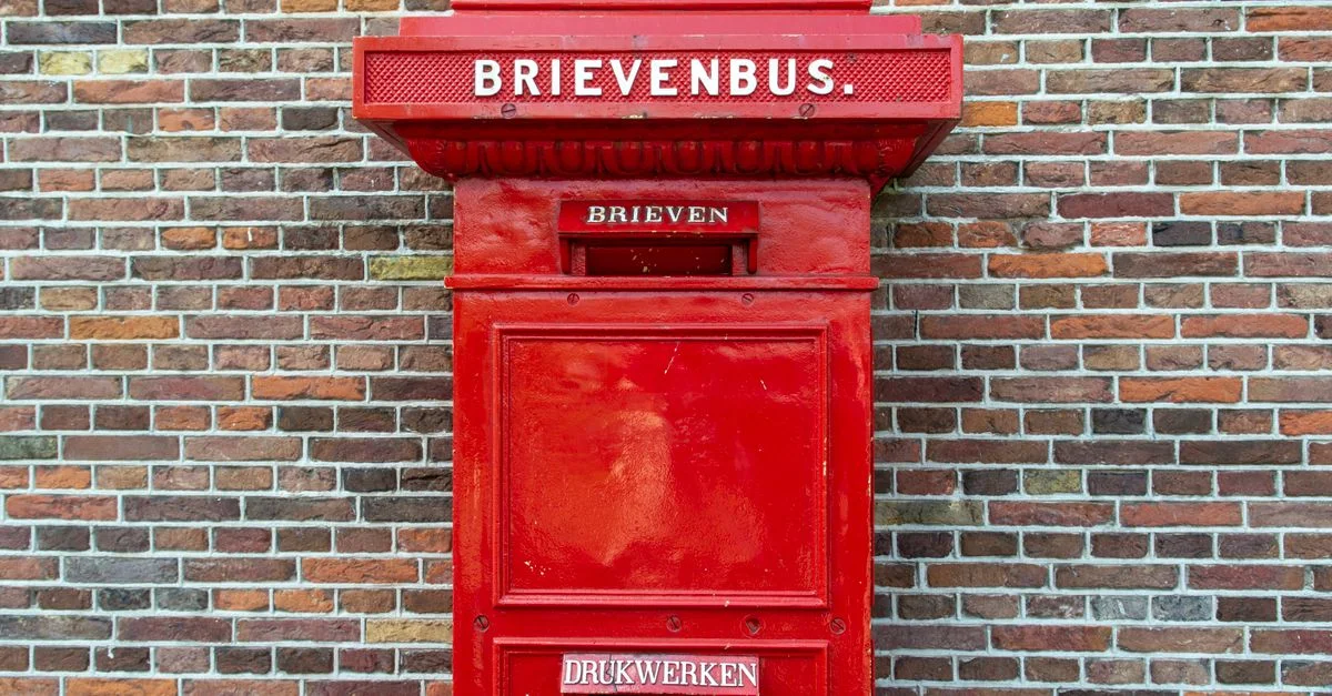 Une boîte aux lettres rouge classique néerlandaise montée sur une façade en briques colorées.