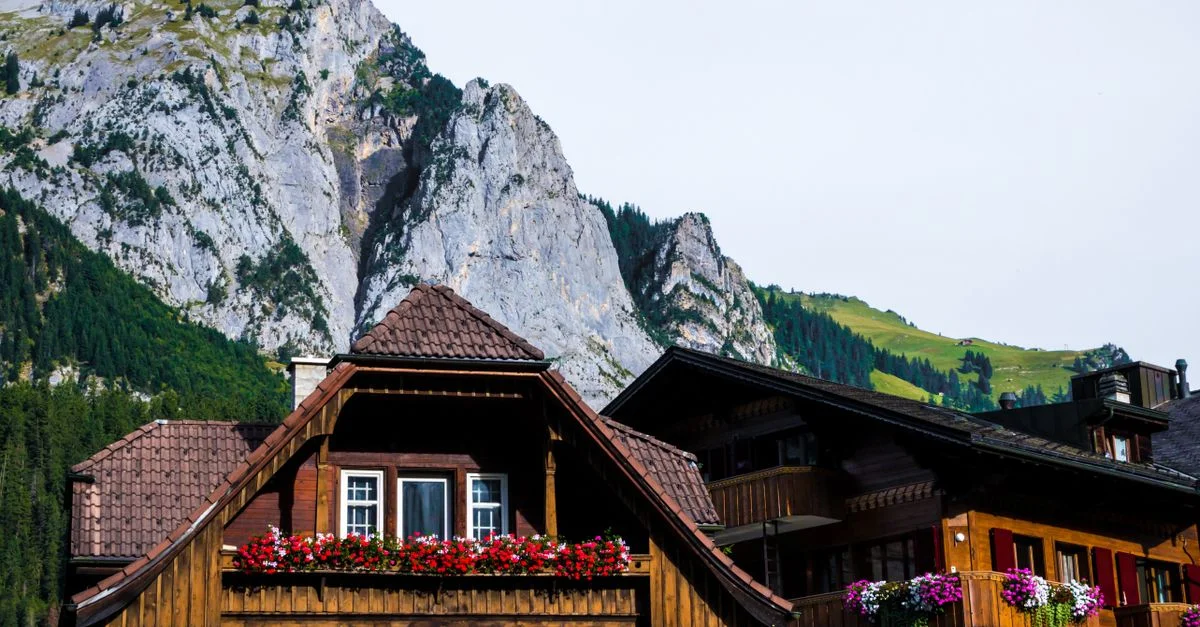 Maisons en bois rustiques avec des jardinières vibrantes, au pied de majestueuses montagnes alpines.