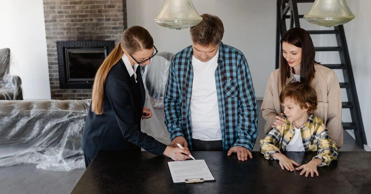 Famille heureuse signant un contrat immobilier avec un agent dans leur nouvelle maison.