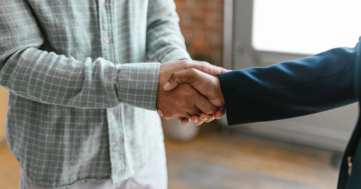 Gros plan de deux professionnels en affaires se serrant la main dans un environnement de bureau moderne.