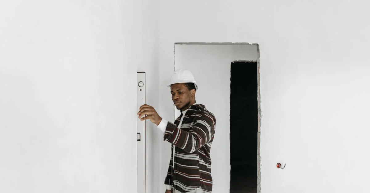 Un architecte portant un casque de sécurité vérifie l'alignement des murs dans un projet de rénovation.