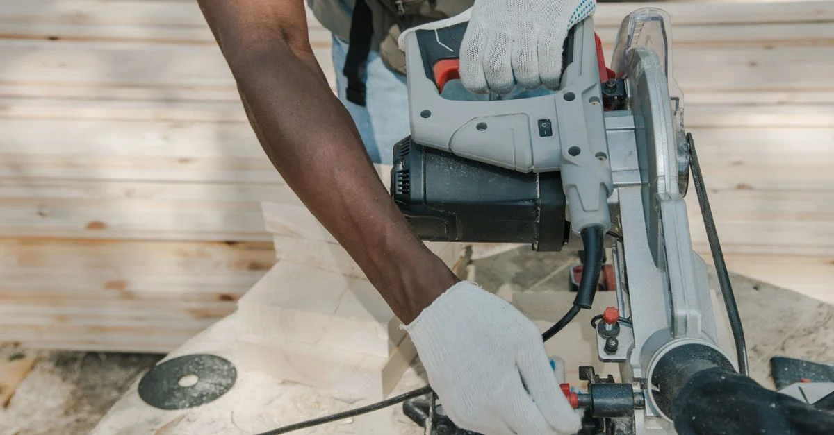 Un ouvrier utilise une scie circulaire pour couper du bois à l'extérieur, mettant en avant des techniques de travail du bois habiles.