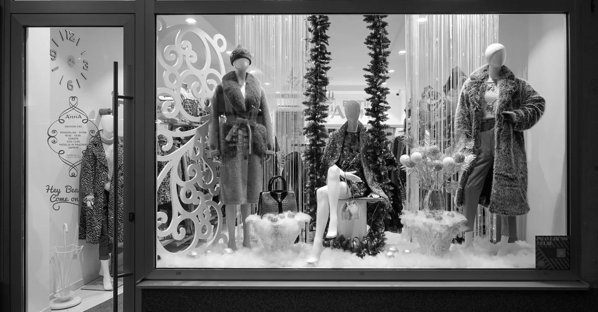 Photo en noir et blanc d'une vitrine stylée avec des mannequins en tenue d'hiver.