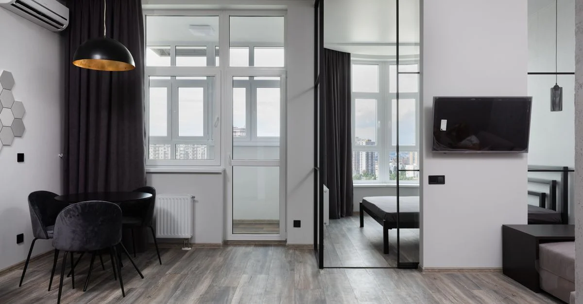 Intérieur d'appartement contemporain avec mobilier élégant et grandes fenêtres offrant une vue sur la ville.