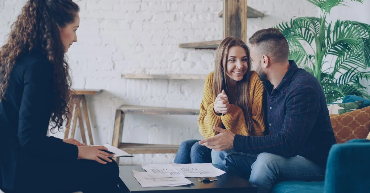Couple souriant discutant de projets immobiliers avec un conseiller dans un cadre moderne et agréable.