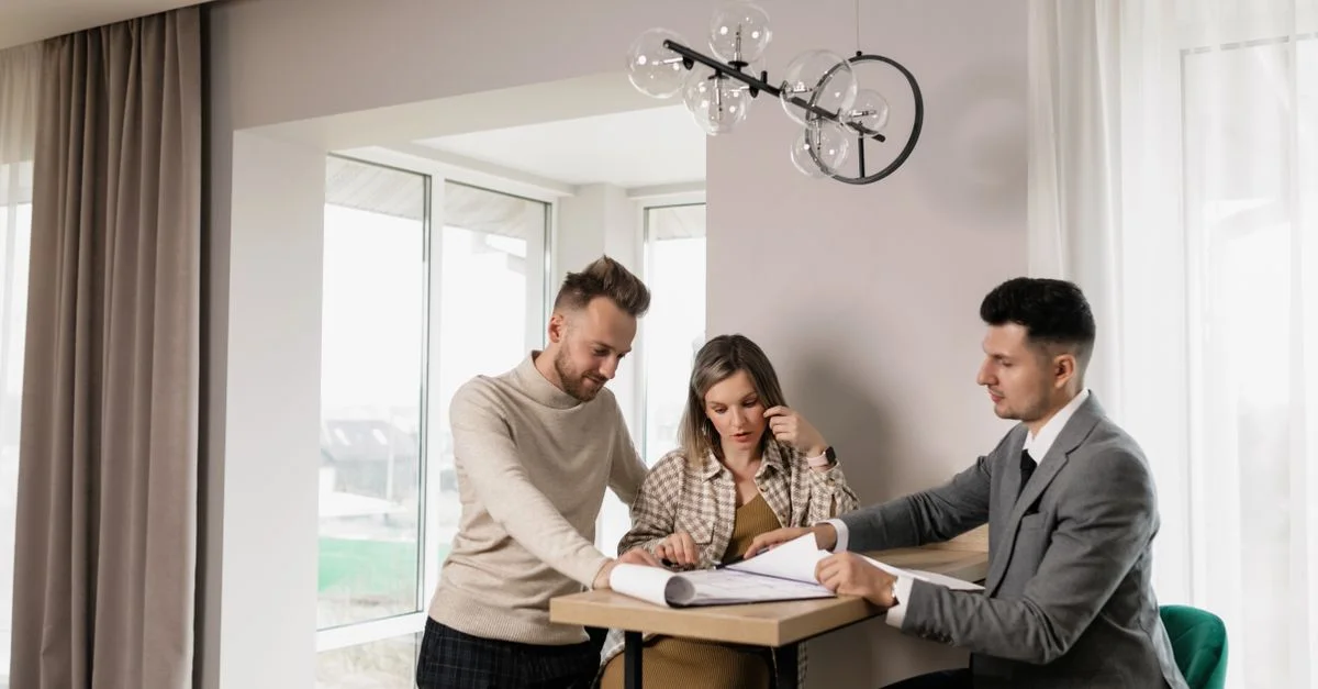 Un couple consulte un agent immobilier dans un cadre moderne, examinant des documents de propriété.