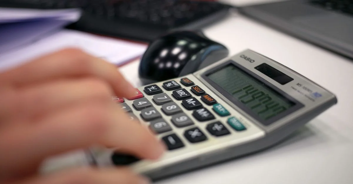 Gros plan sur une main utilisant une calculatrice sur un bureau pour des calculs précis.