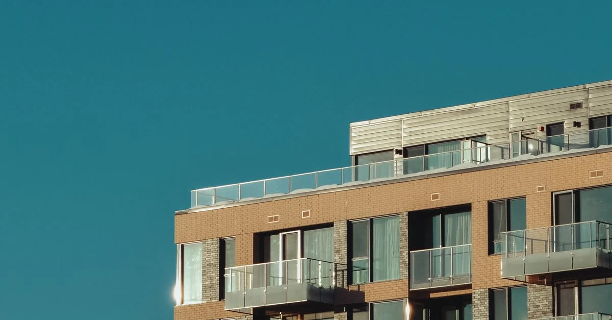 Bâtiment d'appartements urbains élégant avec balcons en verre sous un ciel dégagé.