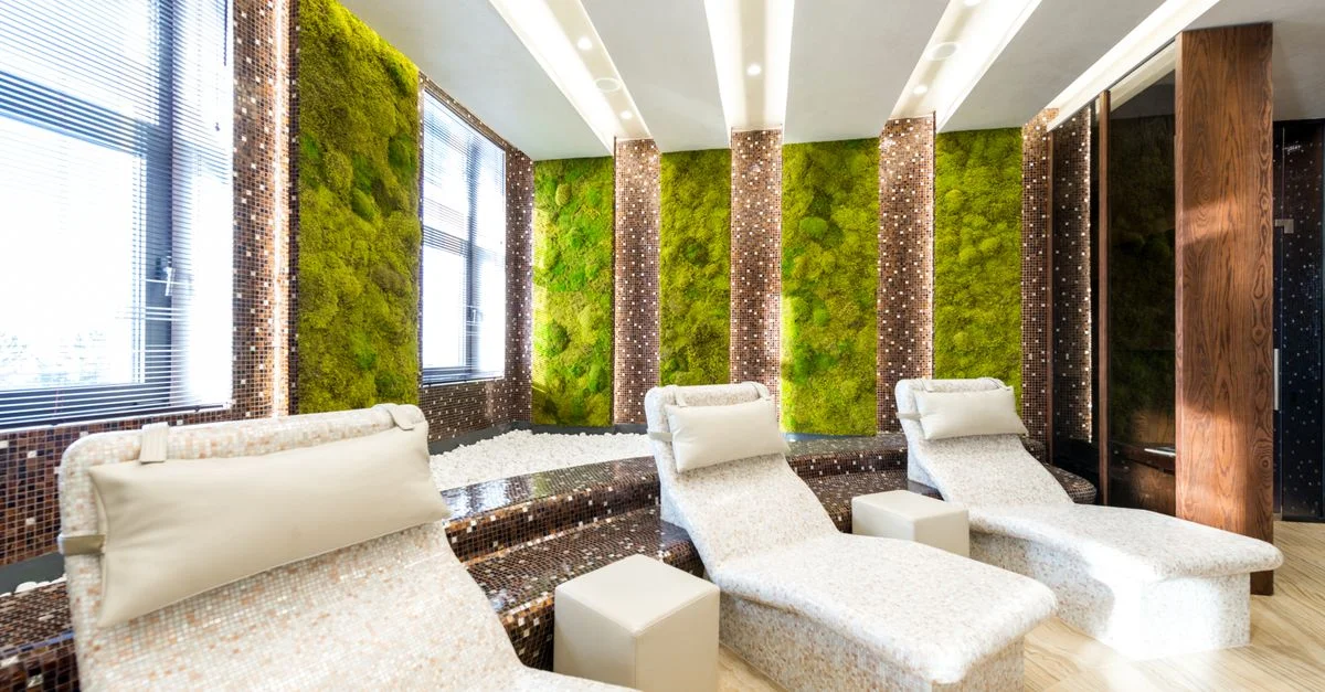 Salon de spa moderne avec des chaises longues confortables et des murs en mousse vibrante pour une ambiance relaxante.